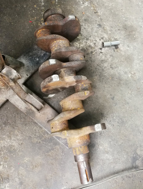 修理车库水泥地面上生锈的旧汽车部件。更换备件运输材料。图片下载