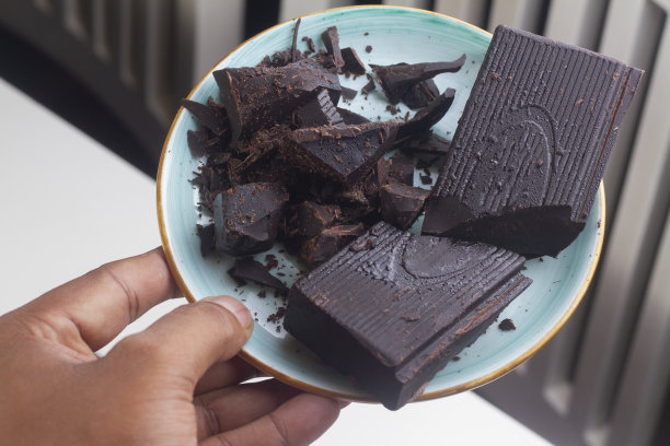 牛奶黑巧克力块孤立在蓝色盘子。图片下载