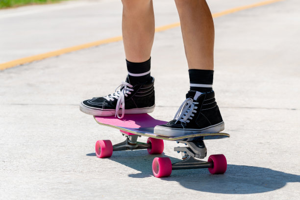 在一个阳光明媚的日子里，一个年轻的亚洲男子正在乡村小路上玩滑板。玩冲浪图片下载