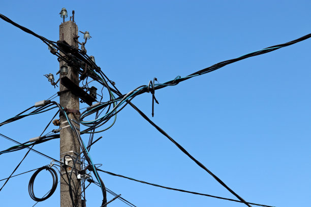 蓝天背景上电线和电容器缠绕的电力线柱图片下载