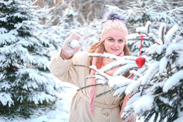除夕夜，在冬天大自然的圣诞树旁打雪球的女人图片下载