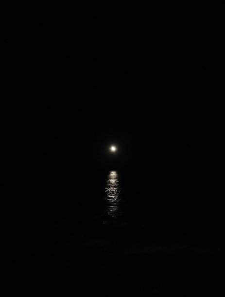 夜晚，满月和昏暗的月光映照在漆黑的海面上图片下载