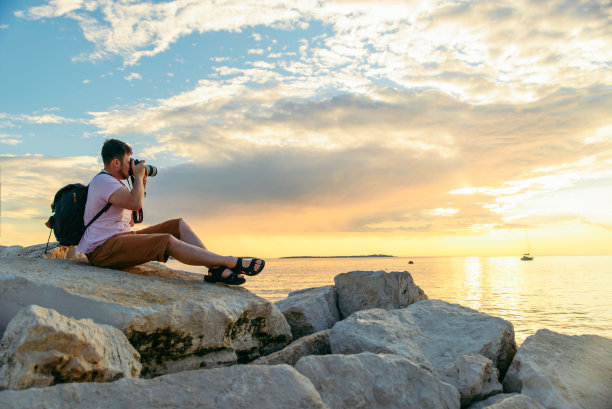 摄影师拿着大相机在日落的海滩上图片下载