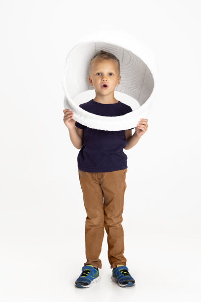 一个学前班的男孩孤零零地站在白色画室背景下。Copyspace广告。童年，教育，情感观念。小的宇航员图片下载