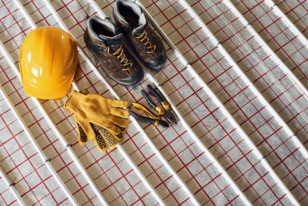 鞋子，安全帽和手套。地板下采暖管道。关闭视图。没有人图片下载