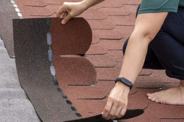 铺设沥青屋顶瓦的妇女。漠视职业健康与安全。图片下载