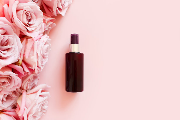 模拟无品牌的棕色塑料化妆品喷雾瓶和粉红色的玫瑰在柔和的粉红色背景。天然有机水疗化妆品，身体喷雾。花平面，俯视图，模型图片下载