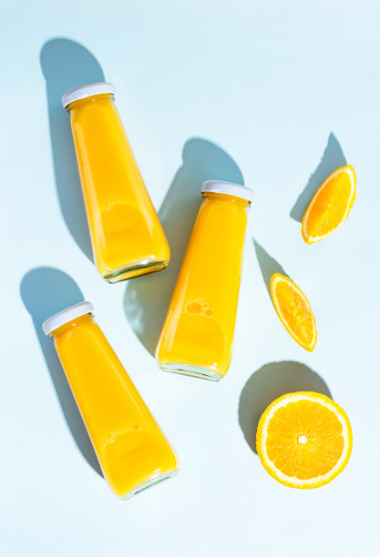 蓝色背景上的瓶装橙汁和橘子。一个多汁，明亮的夏天的概念图片下载