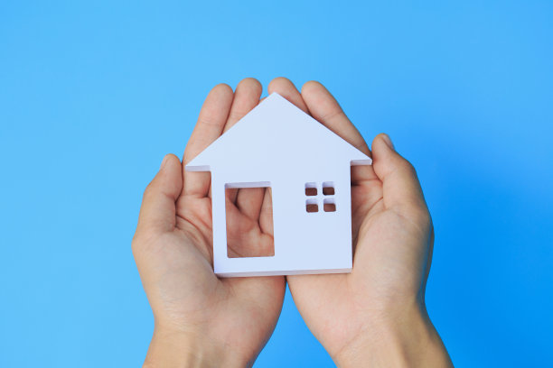 手牵房子在蓝色的背景，家庭和保护保险的概念图片下载
