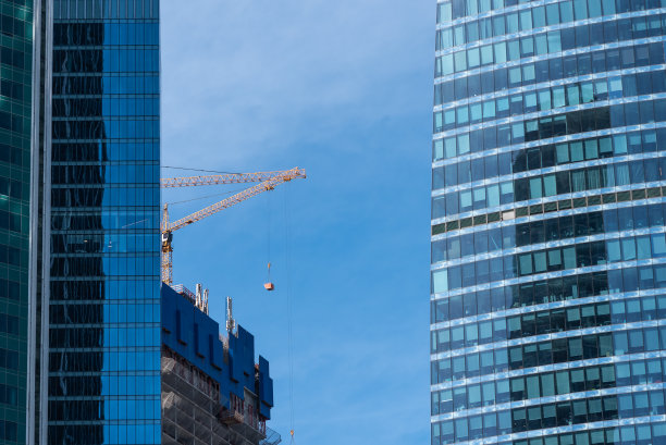 在一个商业中心建造一座新的摩天大楼——高层建筑的起重机和外墙图片下载