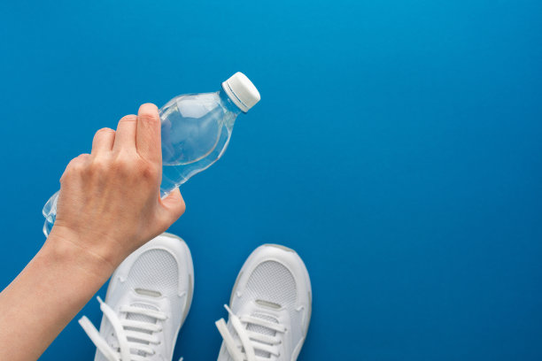 女性手拿一瓶水在健身房图片下载