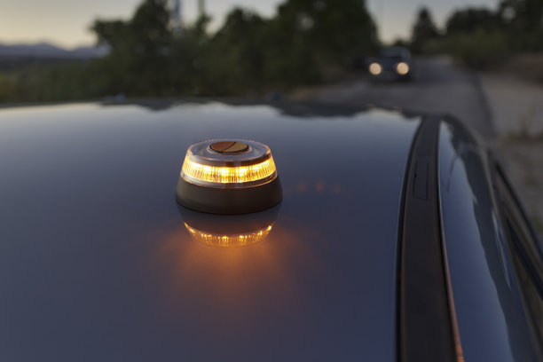 批准的应急灯在黄昏时在车顶发出闪烁的光。背景中一辆车正开着前灯向我们驶来图片下载