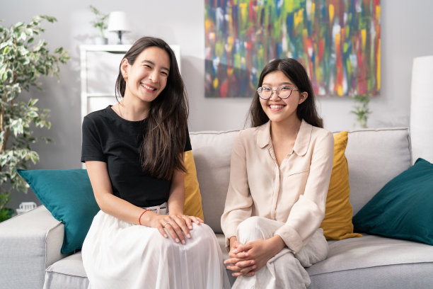 照片中有打扮得体的韩国、日本、亚洲美女，深色头发，雪白的笑容，各个年龄的女孩穿着轻盈宽松的衣服，双手合十放在膝盖上，看着镜头图片下载