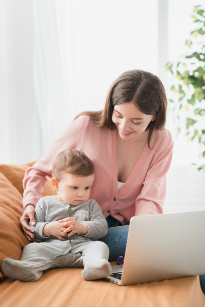 一个单身年轻母亲的纵向肖像与蹒跚学步的新生儿婴儿看卡通片，发展技能想象力，自我发展的节目，电子学习，产假。自由的工作图片下载