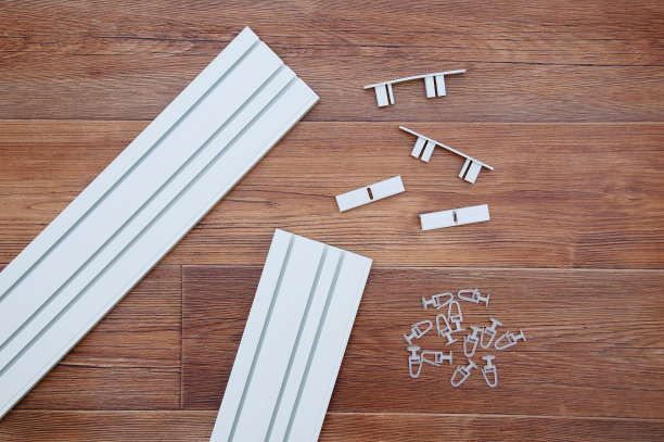 白色塑料天花板飞檐与组装五金和挂钩。棕色木制背景。图片下载