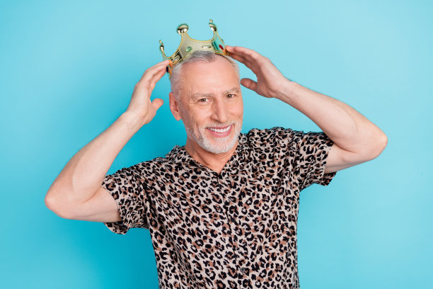 照片中迷人迷人的老人戴着牵手皇冠微笑王子孤立在蓝色背景上图片下载