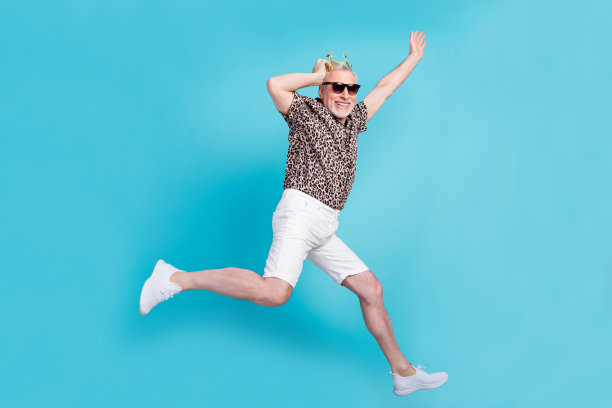 搞笑的中年男子的全长侧面照片跑步戴眼镜衬衫短裤冠鞋孤立在明亮的蓝色背景图片下载