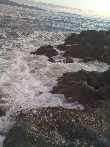 海滩上白色的波浪和岩石的照片图片下载