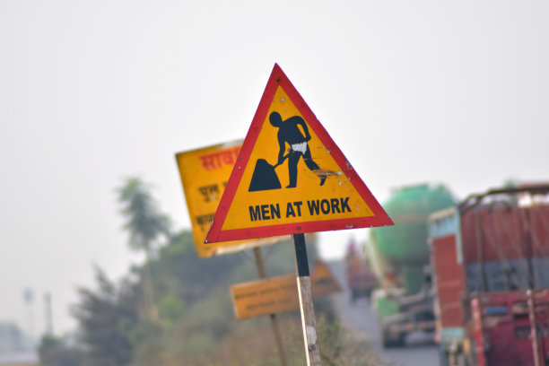 工作进展。道路施工,道路标志。男人在工作中。城市街道上的一些标牌正在施工中。路障和路标。一个工人在工作的剪影。图片下载