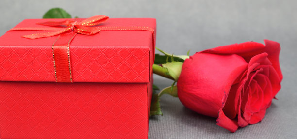 红色礼品盒和新鲜的玫瑰花蕾在黑暗的背景下显示特写图片下载