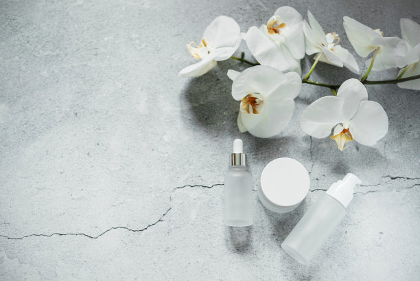 白色玻璃精华液瓶，乳液泵瓶和霜瓶模型在浴室兰花在背景，无品牌化妆品，水疗化妆品品牌模型图片下载