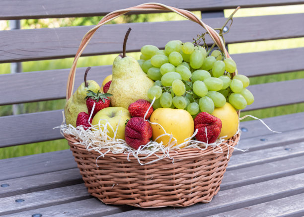 木凳上放着一个装满新鲜水果和浆果的柳条篮子图片下载