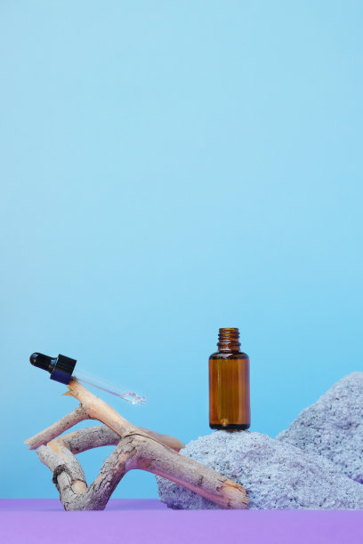 琥珀色玻璃瓶，石木上滴有化妆液，蓝色背景上有面部精华液或面部皮肤护理的透明质酸，在自然的环境中，空间为文字图片下载