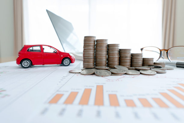 汽车模型和金融图表与硬币和笔记本电脑背景。(金融、汽车贷款及保险概念)图片下载