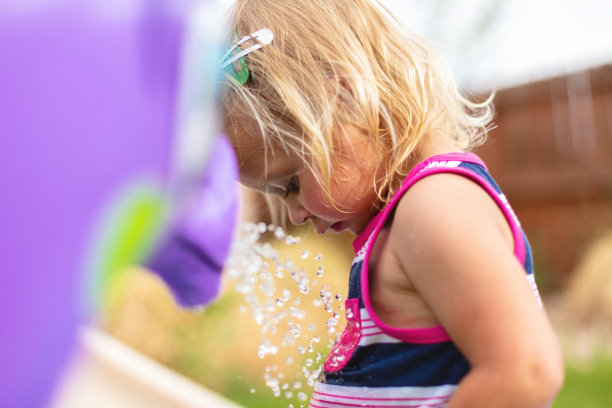 蹒跚学步的女孩在后院儿童游泳池与混合民族家庭玩耍，夏天有趣的照片系列图片下载