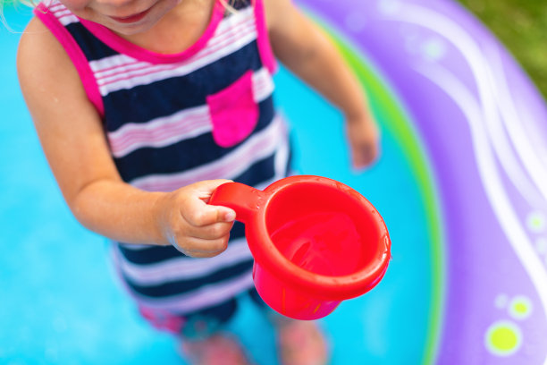 蹒跚学步的女孩在后院儿童游泳池与混合民族家庭玩耍，夏天有趣的照片系列图片下载