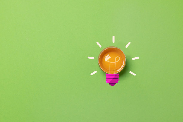 破碎的鸡蛋，在黄色背景上有一个灯泡形状的蛋黄，有复制空间。创意概念图片下载