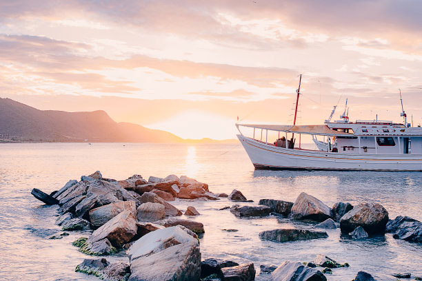 一艘船在沙滩上岩石后面的照片图片下载