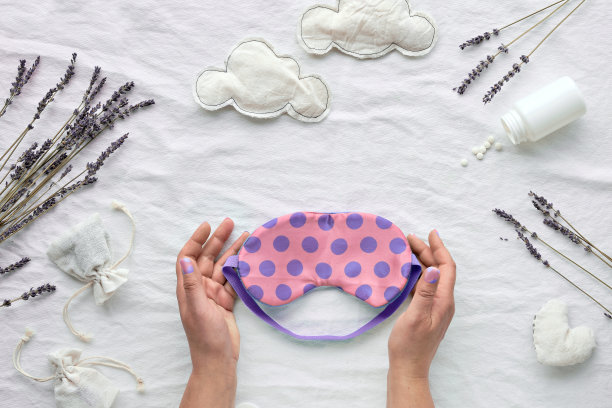 健康的夜间睡眠平躺。粉色带圆点的睡眠面膜。Off white textile background with cotton clouds, heart, sleeping pills, aroma香囊，dry lavender flowers图片下载