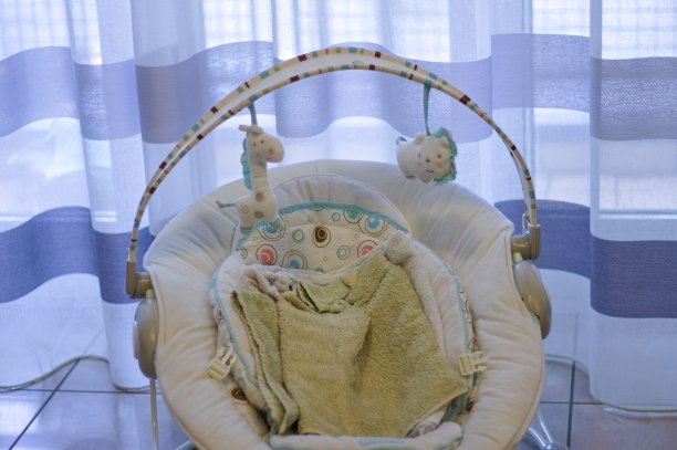 客厅里的条纹窗帘前，一名婴儿保镖在地上放着玩具和毛巾(欧洲，意大利，马尔切)图片下载