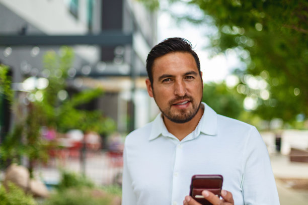 成年西班牙裔千禧一代男性在城市城市人行道上接近沿着城市街道的酒店旅游照片系列图片下载