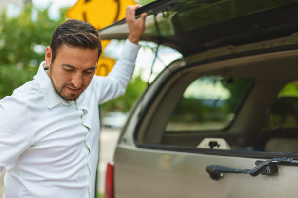 成年西班牙裔千禧一代男性从汽车上卸下行李，沿着城市街道进入酒店旅行照片系列图片下载