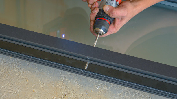 特写:承包商使用无绳电钻在窗框上钻孔。图片下载