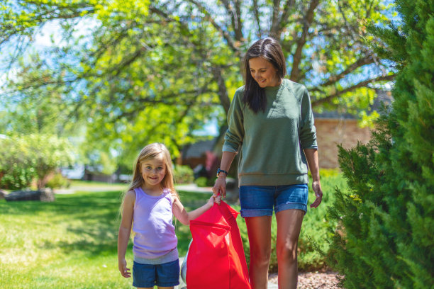 千禧一代的母亲和年幼的女儿一起走，带着室外游戏保龄球瓶，在容器照片系列图片下载