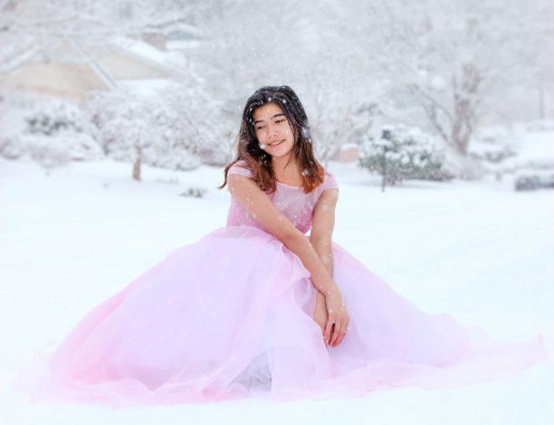 一个穿着粉红色礼服的少女坐在雪地里图片下载