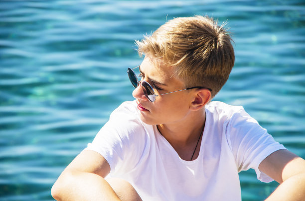 英俊的少年，15-18岁，透过太阳镜看着。图片下载