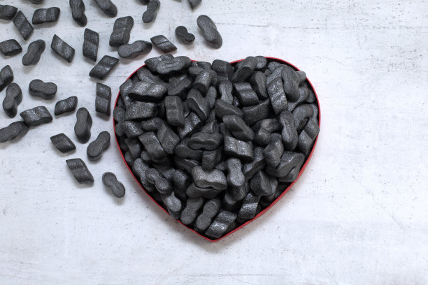 心形卡纸盒黑色包装花生泡沫塑料保护颗粒聚苯乙烯泡沫片背景。爱情或情人节的概念图片下载