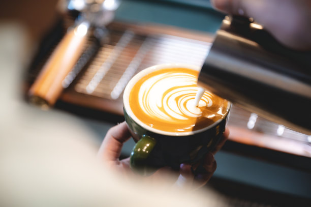 专业的咖啡师用咖啡和牛奶制作拿铁艺术，手拿一杯拿铁，浓咖啡，卡布奇诺，在早餐喝图片下载