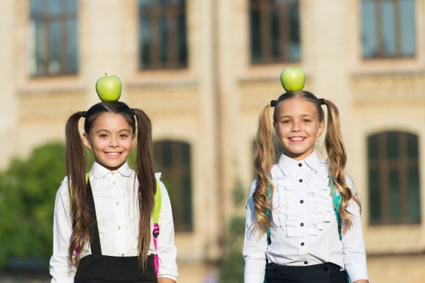 微笑的女生校服，头上戴着苹果，健康的生活理念图片下载
