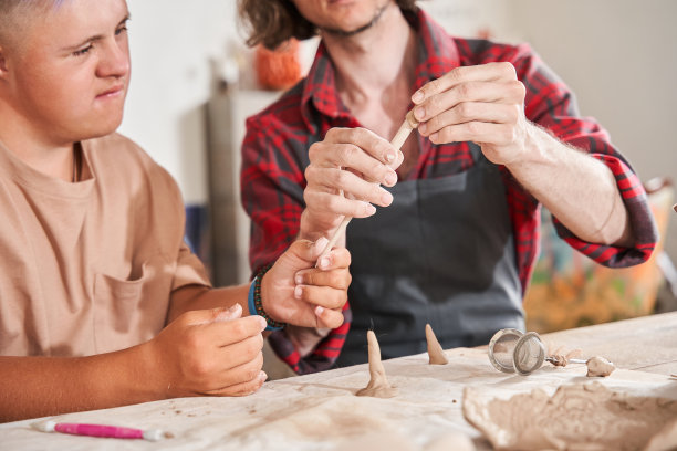 有特殊需要的人在陶艺师的监督下与陶土一起工作图片下载