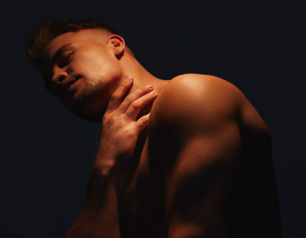 一个英俊的年轻人光着身子站在阴影里图片下载