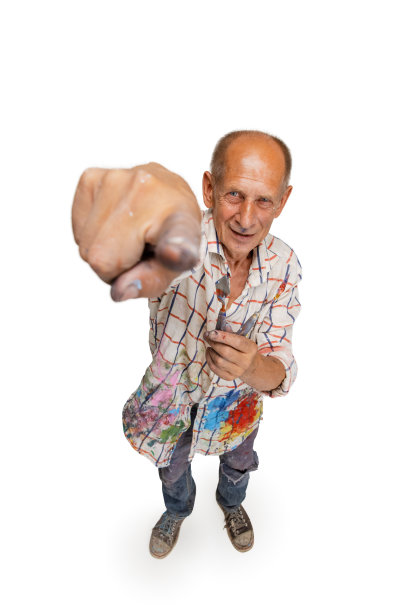 成熟或资深的灰色画家拿着画笔站在镜头前。滑稽的人穿着一件被油漆弄脏的衬衫到处闲逛，孤立在白色上图片下载
