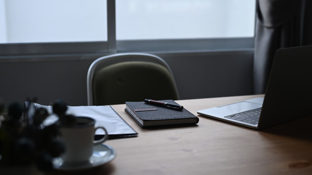 有笔记本、笔记本电脑和咖啡杯的办公桌。图片下载