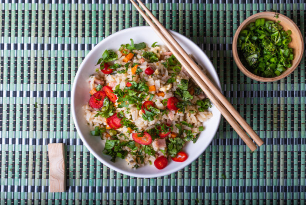 猪肉和蔬菜炒饭，在筷子碗里撒上香草和辣椒——这是一种非常常见的亚洲菜，俯览在竹制餐巾上图片下载