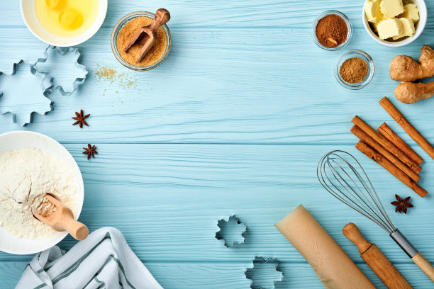 在蓝色木桌上摆放姜饼面粉、鸡蛋、厨房工具、器皿和饼干模具的烘烤背景。前视图。平的风格。模拟。圣诞烘烤。图片下载