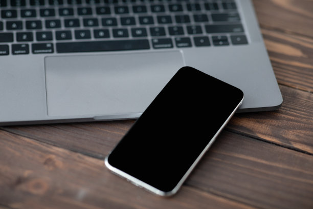 现代智能手机的黑屏放在笔记本电脑附近，特写。为你的设计或广告制作模型图片下载
